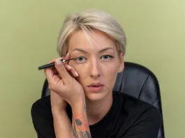 Eine Hand, die einen ungiftigen Eyeliner auf ein Augenlid aufträgt, um einen präzisen Look zu erzielen.